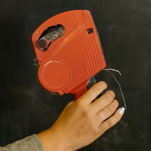 10. Say My Name Red labeller held by a female hand against a black background