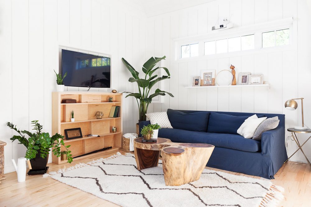 Cottage Vibe white living room with navy slip covered sofa under window and plant in corner