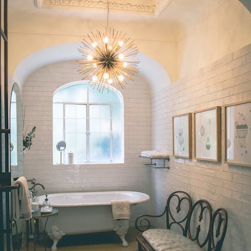 Let There Be (Luxe) Light A cozy bathroom with an arched wall and a chandelier