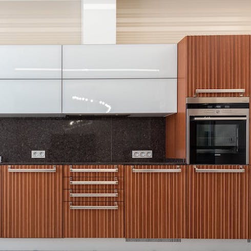 Fluting, Fluting and More Fluting A sleek wall of kitchen cabinets with white upper cabinets and fluted wood cabinets