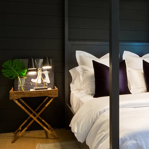 Black Out Chic bedroom with black panelled walls and a black four poster bed with white sheets as featured on Property Brothers for Home Network.
