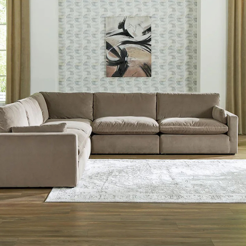 No Sag Time Cloud couch dupes featuring Ashley Home Store's Sophie 5 Piece Modular Sectional sitting in a living room with oak floors, a white rug, wallpaper on the wall behind with hung art and tall chartreuse drapes