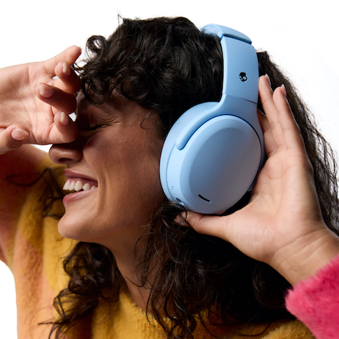 Block It Out A woman with dark curly hair wearing a yellow sweater listens to blue Skullcandy Crusher ANC 2 Sensory Bass Headphones with Active Noise Canceling as part of HGTV's 10 Gift Ideas for the Women in Your Life
