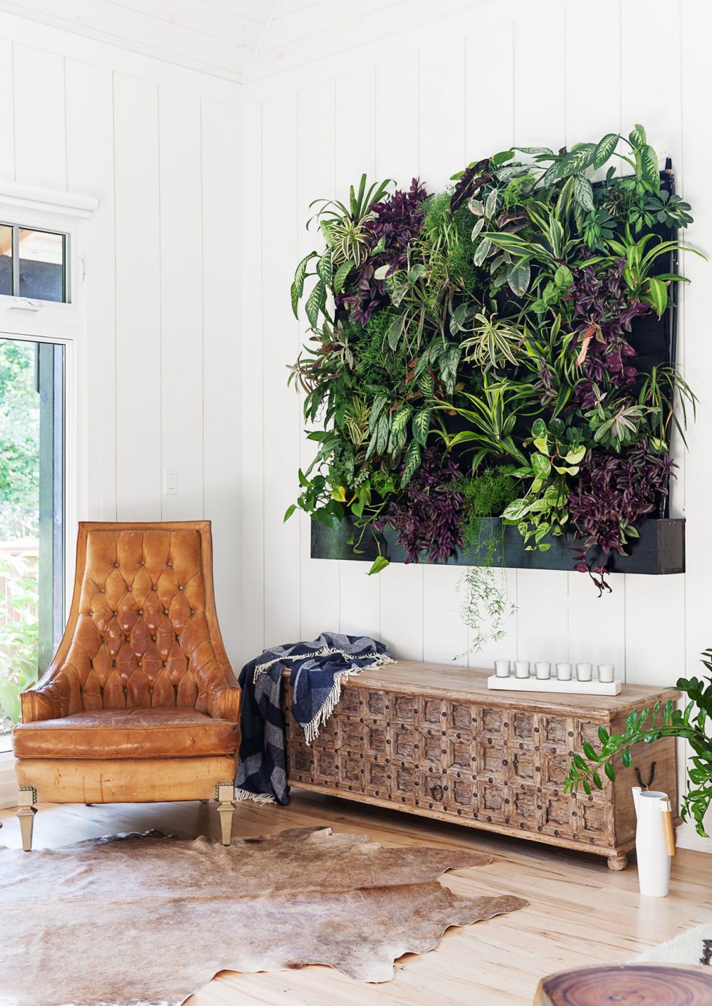 Against a Wall living wall of plants beside tan tufted leather chair