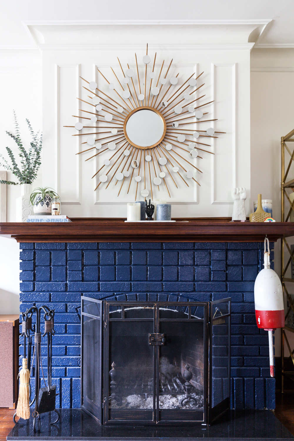 Radiating Decor Retro fireplace design with blue-painted brick and vintage sunburst mirror above mantel.