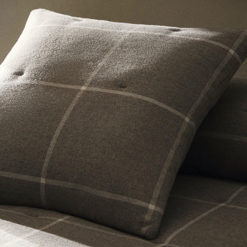 Throw Down Grey and white flannel throw pillow cover with a check print on a bed in a darkened room