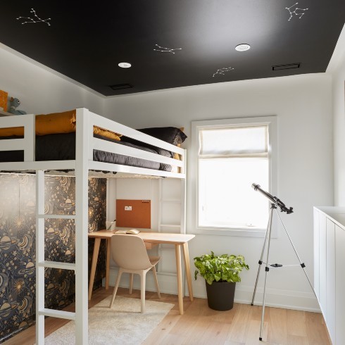 Star Light Children's bedroom with loft bed and star constellations on ceiling, a wooden desk and chair, a potted plant, wood floors, a small white rug, a window with roman blinds, and a telescope on a stand