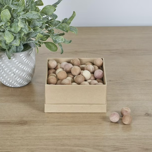 8. Bug Off Neatfreak! Natural Cedar Balls sit on a wood floor beside a cedar branch in a grey pot