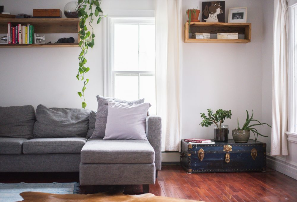 Hanging Around grey sectional in front of window beside blue trunk on floor