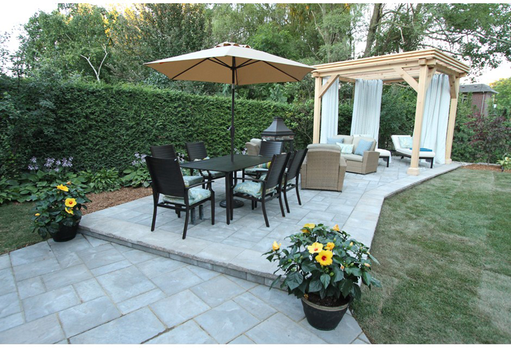 A Classic Hedge A backyard patio with a dining set, conversation set and pergola. A hedge fences in the patio area.