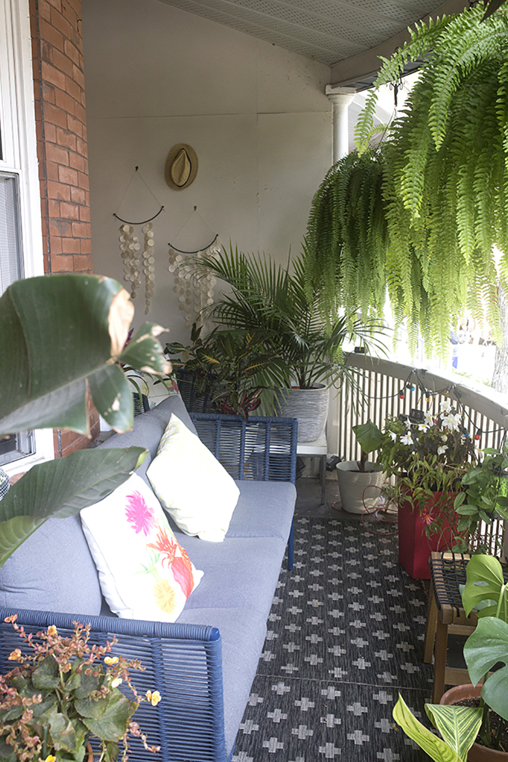 Leafy Hanging Plants A balcony with many plants around. Hanging from the ceiling are two large ferns.