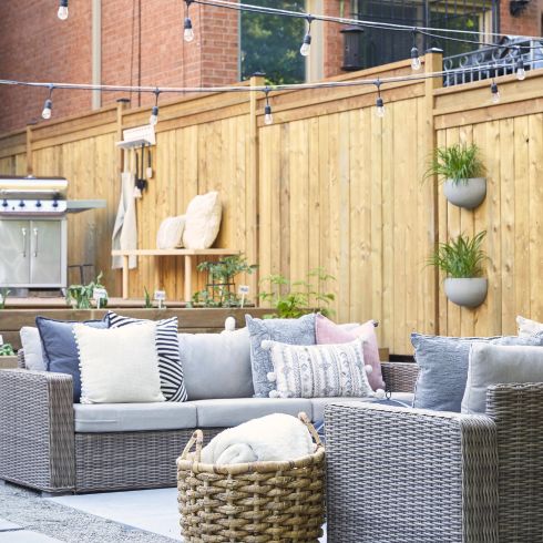 Mistake #1: Not Planning Your Outdoor Space in Advance Small backyard with hardscaping, modern grey couch and string lights.