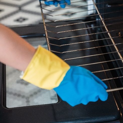 Ovens and Stovetops A person wearing rubber gloves while cleaning an oven