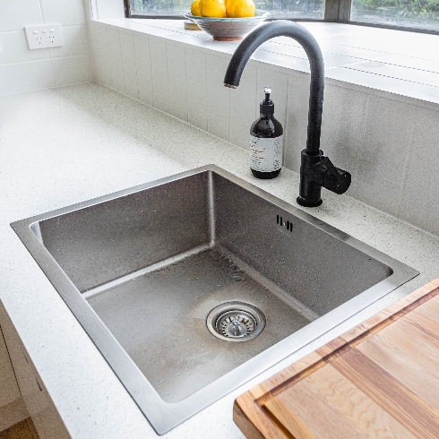 Sinks and Drains A stainless steel kitchen sink with black faucet and tap
