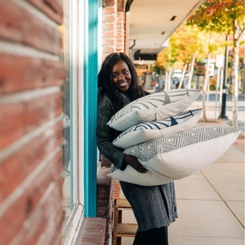 Batiqua Linda Adimora, founder of Batiqua, smiling while holding pillows from her brand