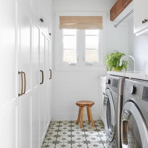 Build a Laundry Room Near the Bedrooms Narrow laundry room with white cupboards and white and black tile floor
