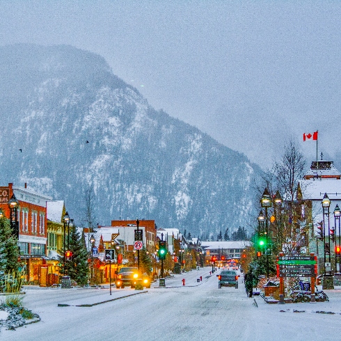 Banff, Alberta A street in Banff, Alberta with colourful buildings, decorated trees and snowy mountain backdrop.
