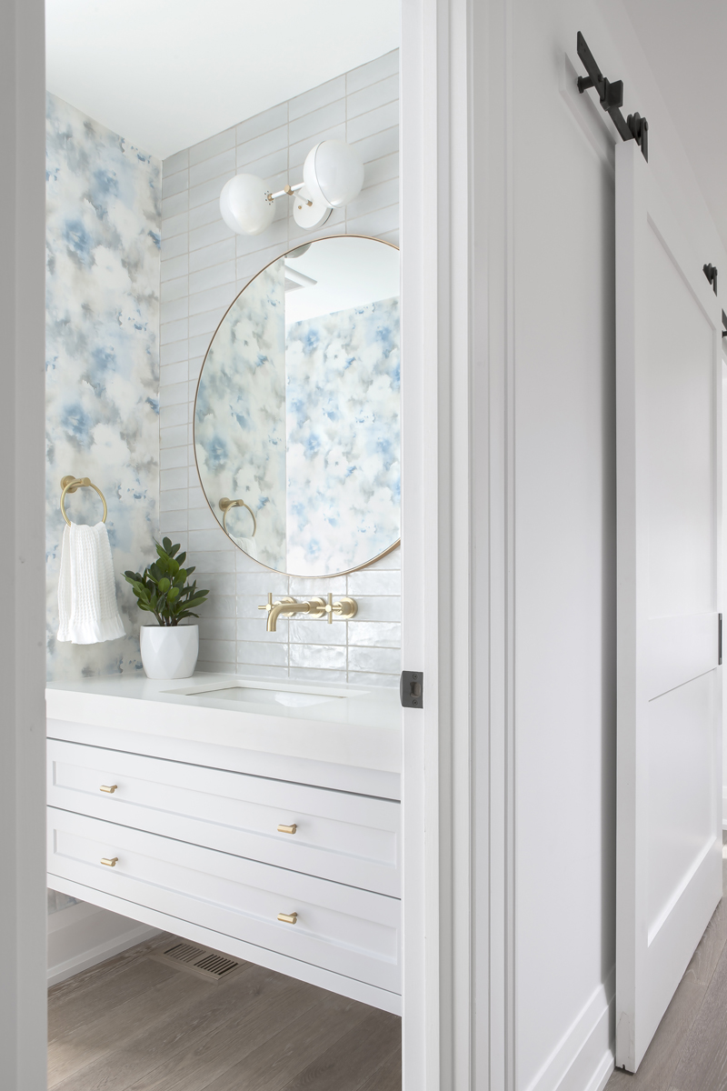 Flower Power A powder room with a wallpapered accent wall and brass faucet and cupboard handles