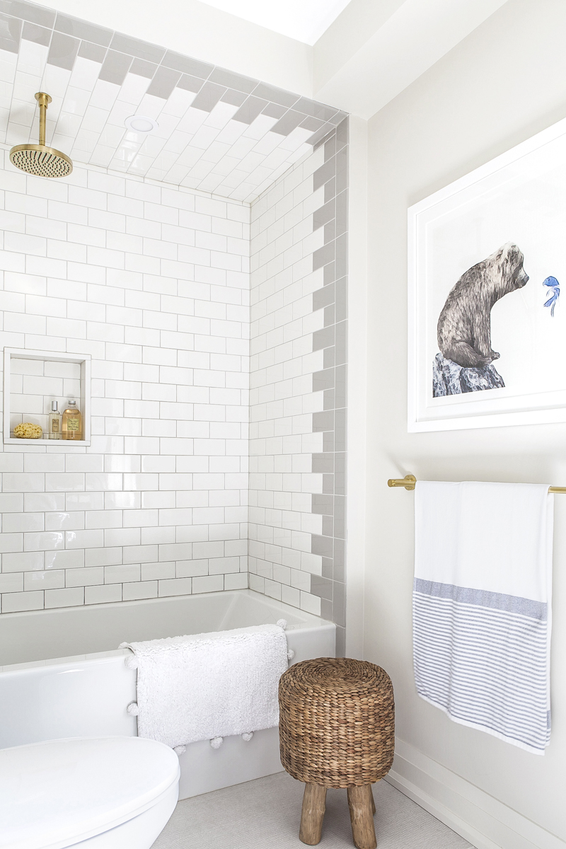 Pin It Newly renovated bathroom with white-and-grey tile work and brass shower head