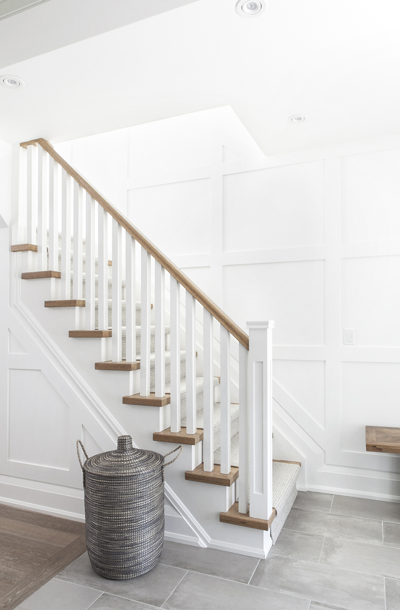 Warm Welcome A neutral-toned entryway with a carpet runner on the staircase and grey floor tiles