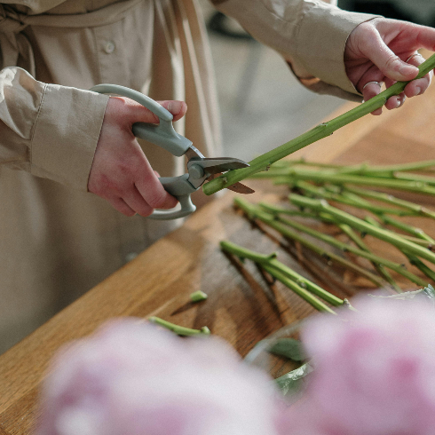 Cut Stems on an Angle A person cuts the stems of fresh flowers with a pair of scissors