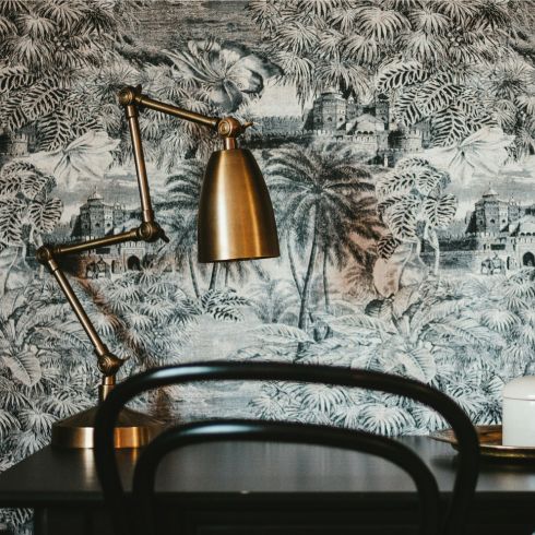 Play With Patterns Black and white decorative wallpaper featured above a table and a brass lamp.