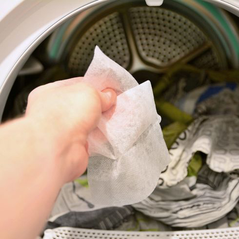 12. Dust With Dryer Sheets a person putting a dryer sheet into the dryer