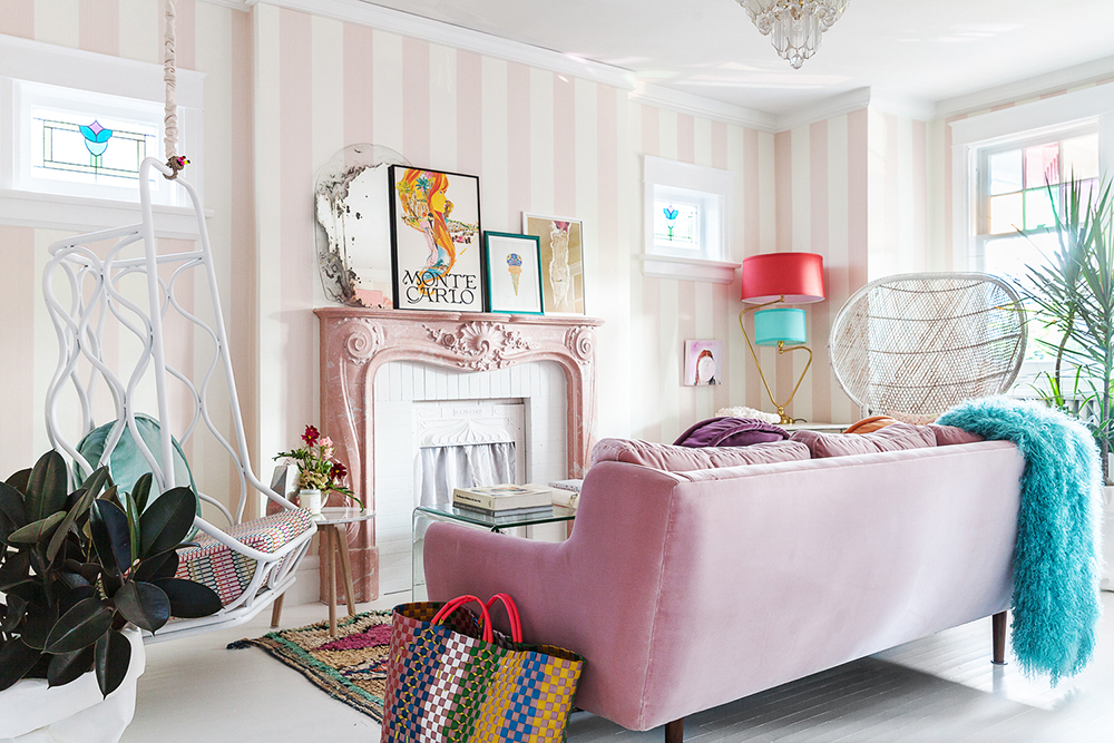 Play up a Petite Curtain Colourful living room with pink-striped walls, a pale pink fireplace and pink velvet couch. Inside the fireplace is a white curtain.