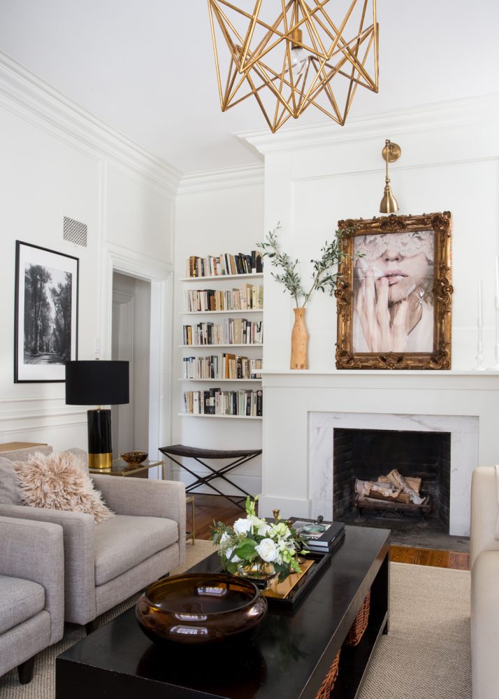Curate an Art Display Neutral living room with white walls and light beige furniture. Above the white fireplace is a portrait in a gold statement frame.