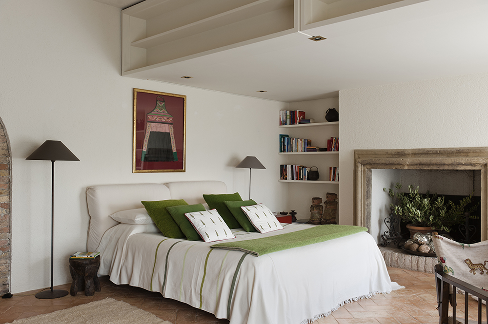 Add a Pop of Green With a Potted Plant Minimalist white bedroom with fireplace. A potted plant fills the space inside the fireplace.