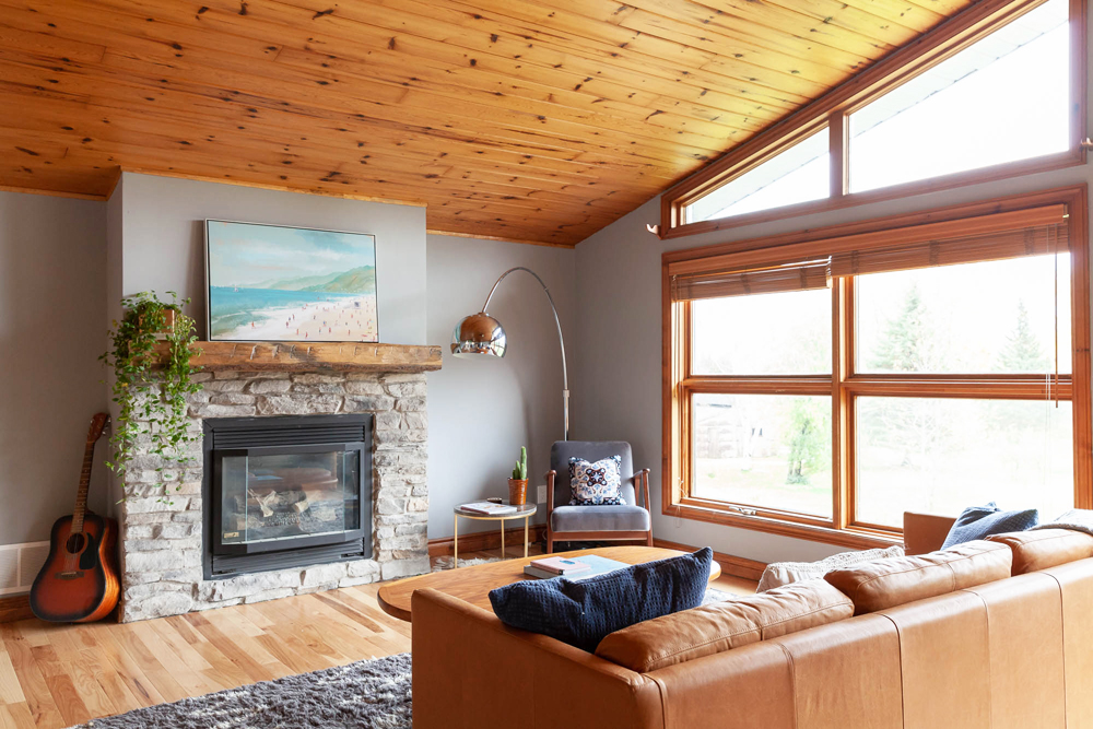 Style Your Mantle With Trailing Plants Bright living room with wood ceiling and stone fireplace. A plant with trailing vines sits on the fireplace mantle.