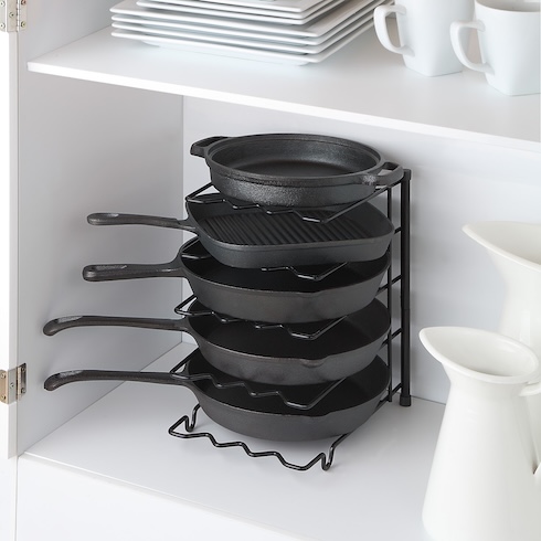 Capitalize on Cupboard Space Four black frying pans are stacked on a black pan organizer