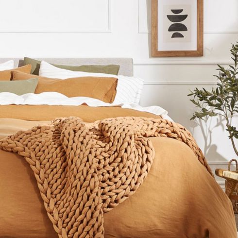 Layered Textures Bedroom with burnt orange sheets and cozy throw with white aesthetic