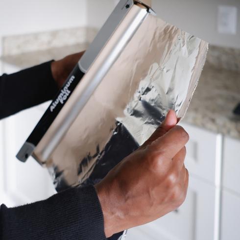 3. Use Foil to Foil Messes a person pulling tin foil out of a box