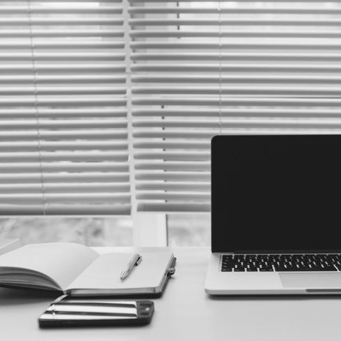 19. Use Socks to Clean Blinds a notebook and a laptop on a white desk with blinds