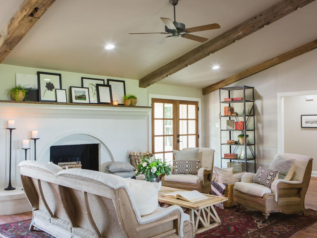 Lean On Me Living room fireplace that stretches along one wall with mantel adorned with picture frames and potted plants.