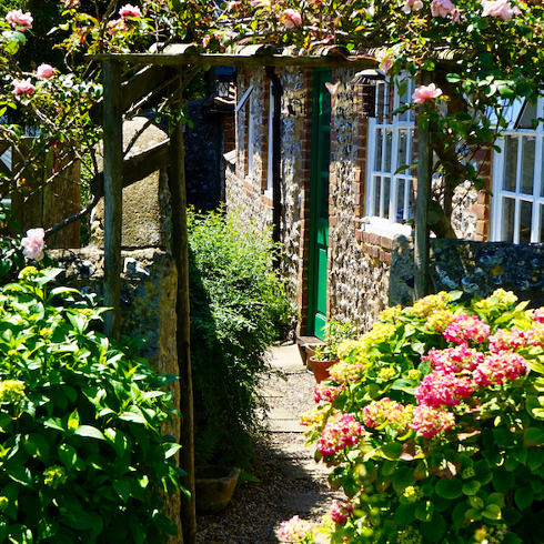 Add Interest With a Trellis A lush front garden with a wooden trellis and plants growing around it
