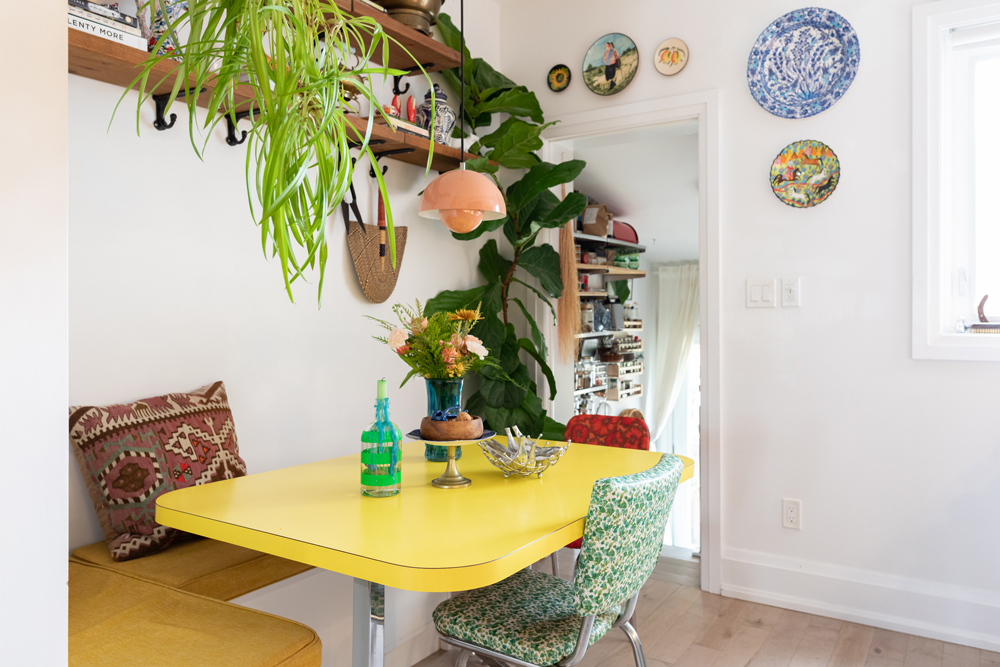 Power-Clashing Perfection white kitchen space with yellow table and wooden shelves on wall