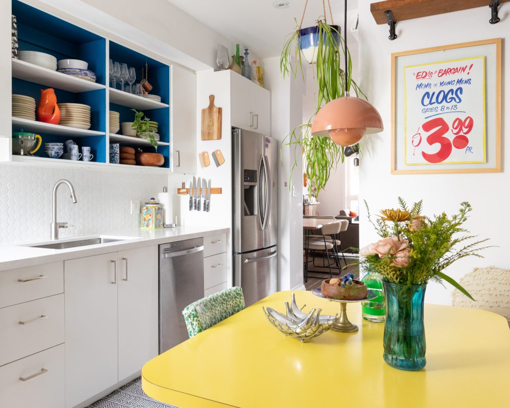 Kitchen Kitsch white kitchen space with yellow table and wooden shelves on wall