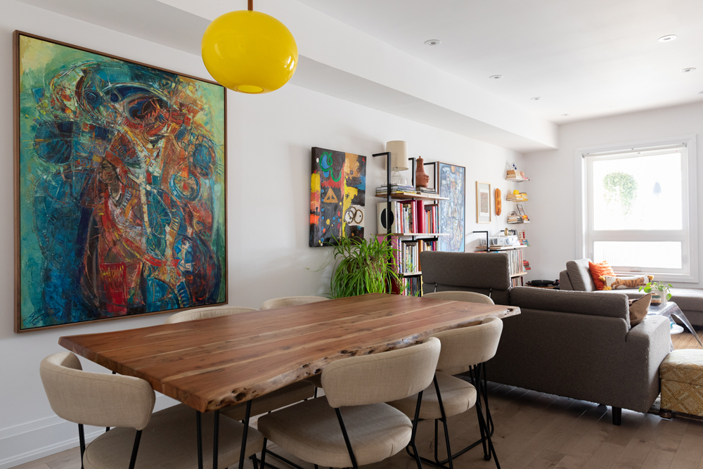 Going With the Flow White dining room with wood table and yellow hanging light