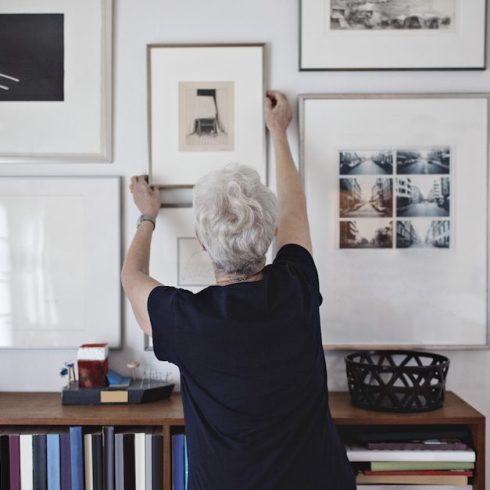 Step Three: Check Your Frame woman hanging pictures on wall over bookshelf at home
