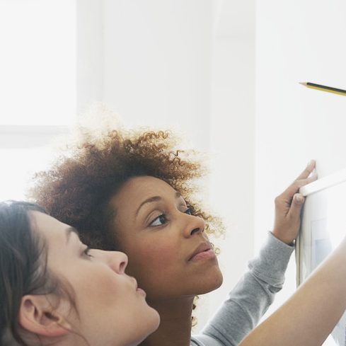 Level Up women using level to hang picture on wall