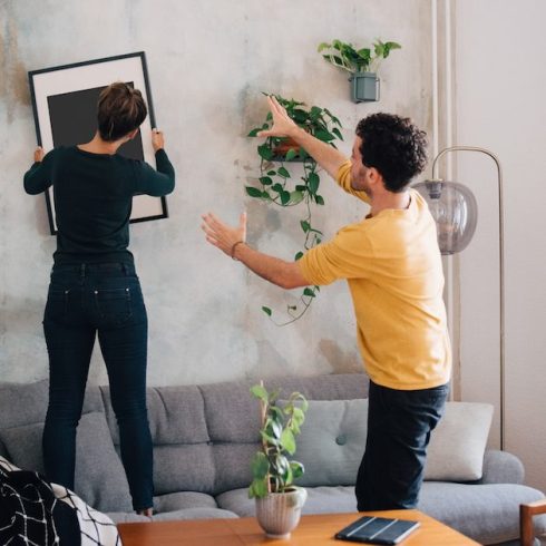 Step Four: Plan Your Placement man guiding woman in hanging picture frame on wall