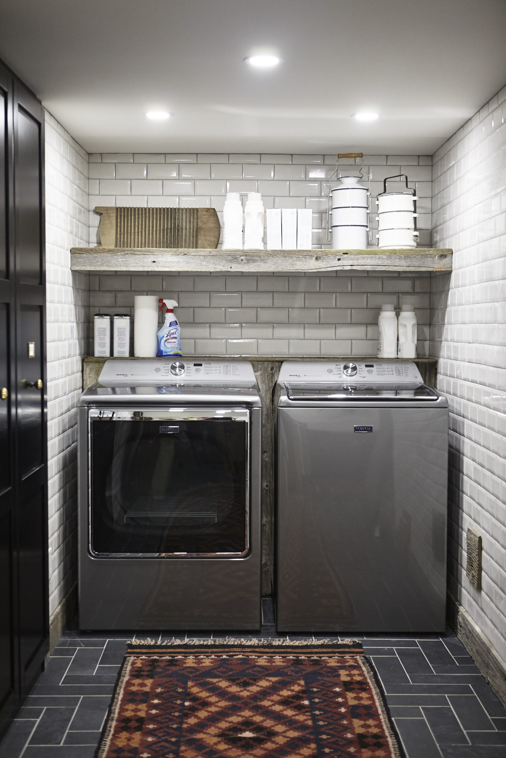 Tile Style laundry room with floor-to-ceiling white subway tiles and wood open shelving.