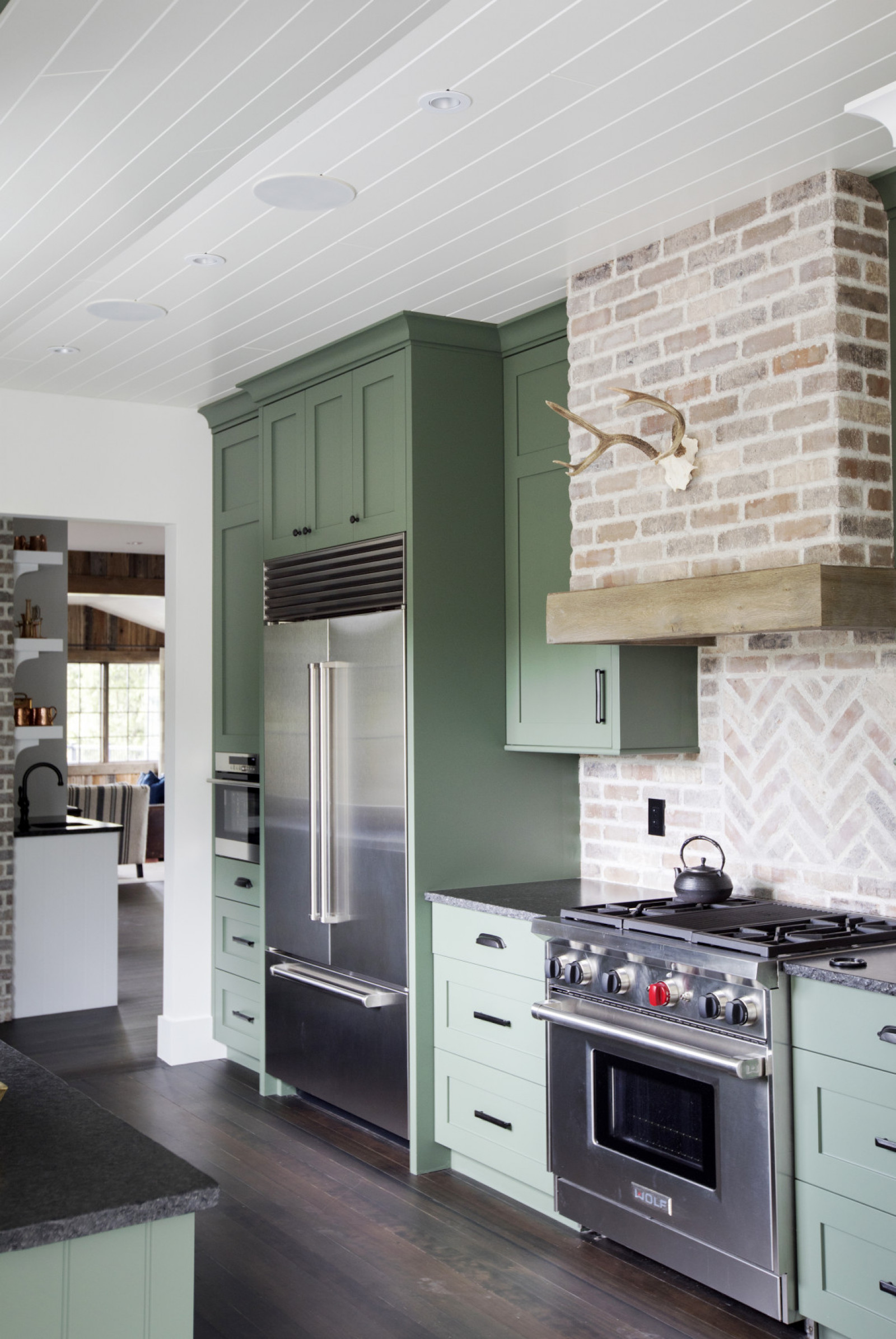 Brick by Brick green cabinet kitchen with pale brick backsplash and animal skull over wolf range