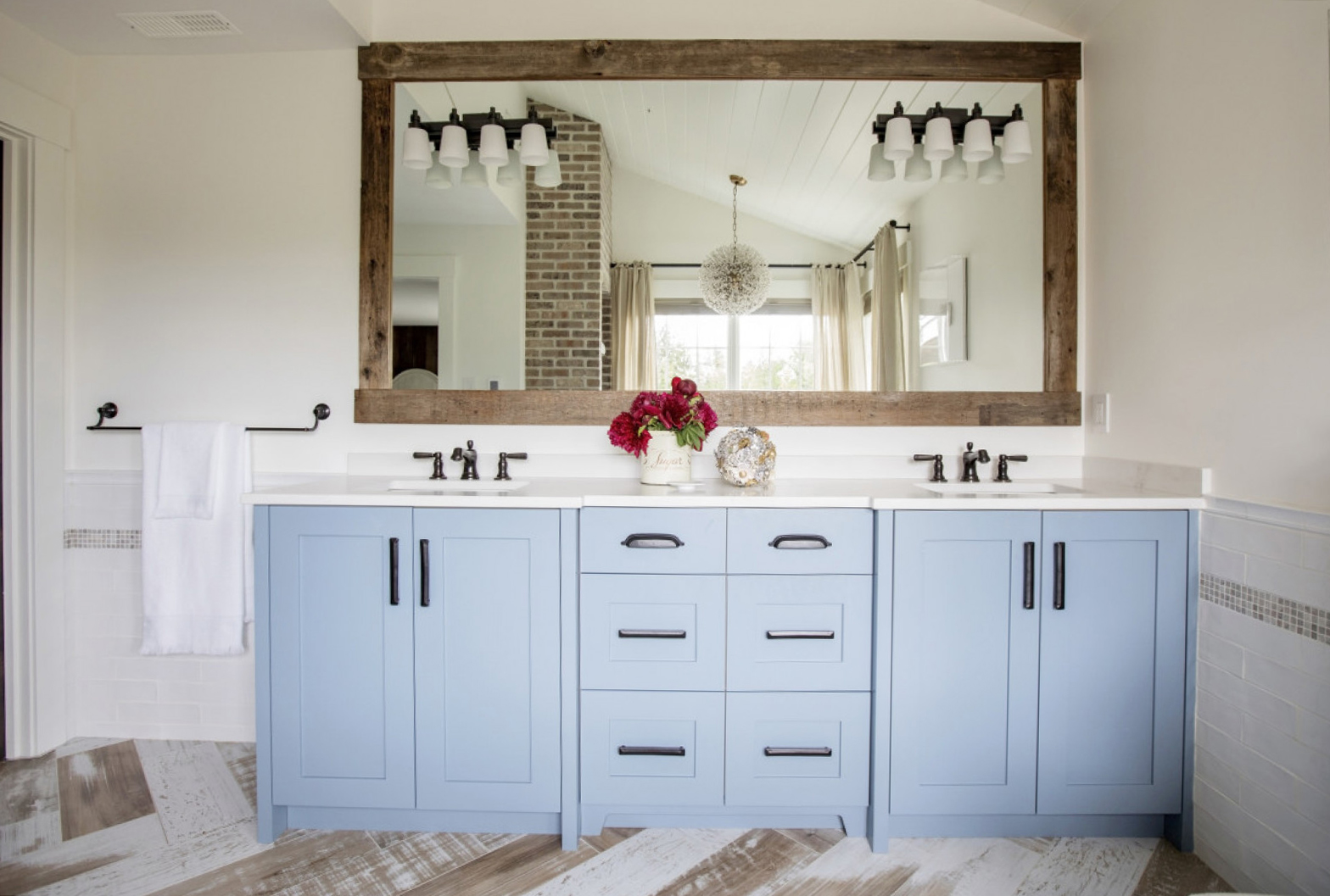 Blue Notes double sink vanity, blue cabinets, black hardware, red flower arrangement