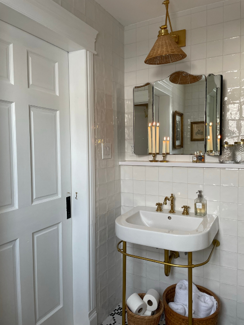 Getting It Right A bathroom sink with a mirror, overhead rattan pendant light and baskets of towels and toilet paper below the sink