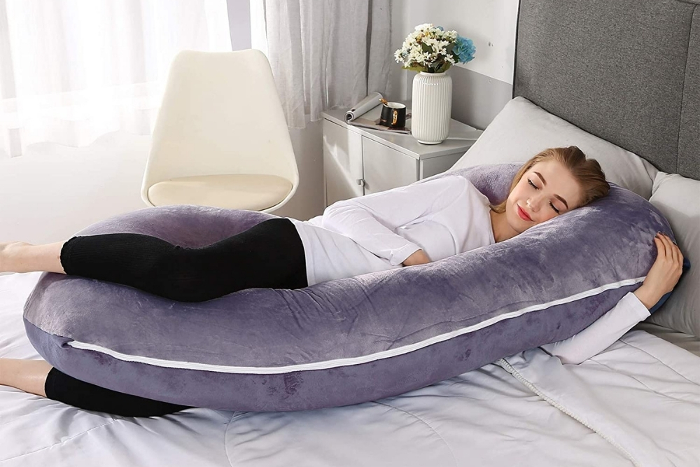 The Best Pillow for Pregnancy and Postpartum A woman smiling in her sleep using a purple pregnancy pillow.