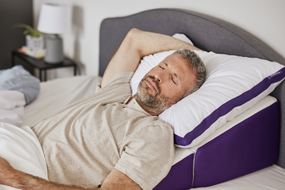 The Best Pillow for Sleep Apnea or Heartburn A middle aged man sleeping on the Polysleep Wedge pillow.
