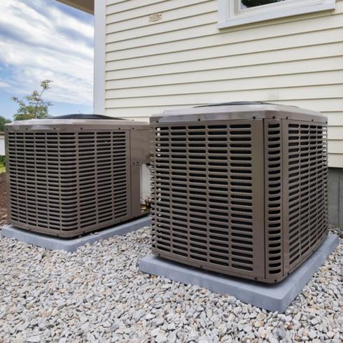 New Plumbing or HVAC Systems Two air-conditioning units side-by-side in the backyard of a house
